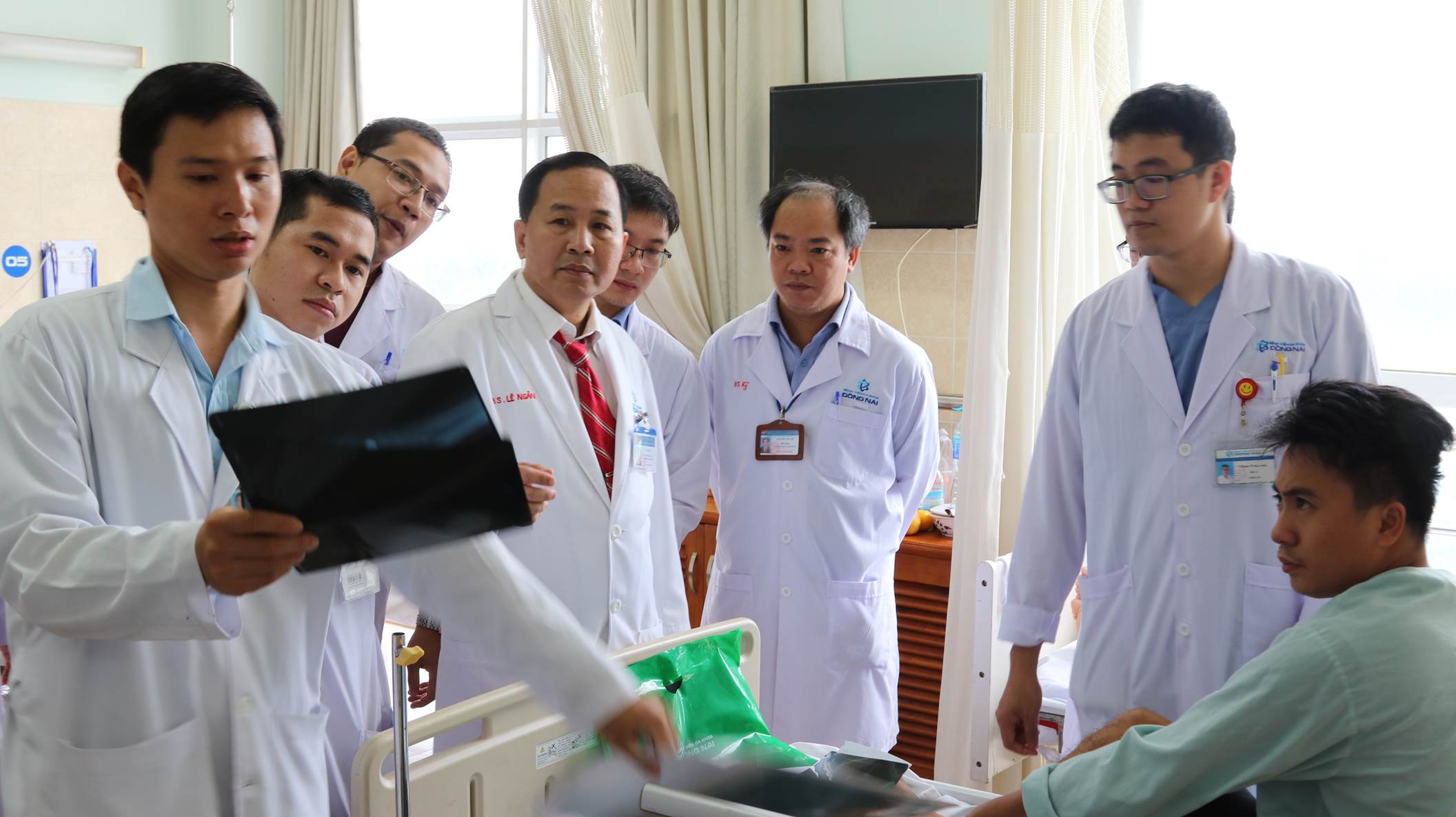 A group of doctors standing around a patient
Description automatically generated with medium confidence